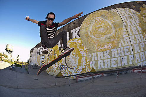 Germany, North Rhine-Westphalia, Duisburg, Skateboarder performing trick on ramp at skateboard park - KJF000158