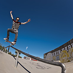 Germany, North Rhine-Westphalia, Duisburg, Skateboarder performing trick on ramp at skateboard park - KJF000159