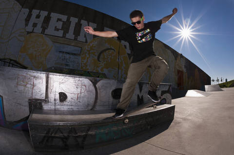 Germany, North Rhine-Westphalia, Duisburg, Skateboarder performing trick on ramp at skateboard park stock photo