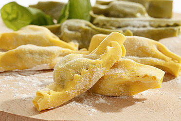 Candy shape pasta with flour and basil leaf on chopping board - CSF015477