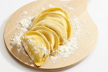 Crescent shape pasta with flour on chopping board - CSF015483