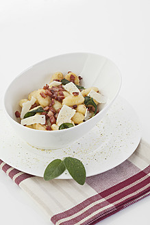 Gnocchi und Speck mit Serviette auf weißem Hintergrund - MAEF004059