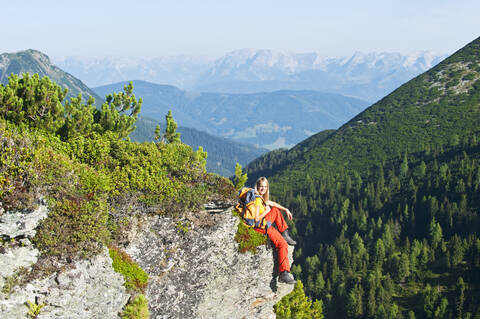 Österreich, Salzburg, Wanderer auf Fels sitzend, Porträt, lizenzfreies Stockfoto