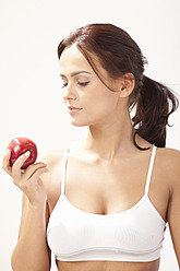 Junge Frau betrachtet einen Apfel - MAEF004104
