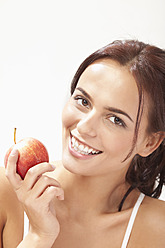 Young woman with apple, smiling, portrait - MAEF004106