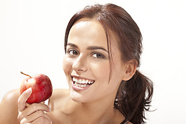 Young woman with apple, smiling, portrait - MAEF004107