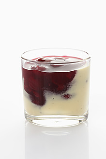 Glas mit roter Grütze und Vanillesoße auf weißem Hintergrund - CSF015650