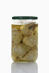 Preserved artischoke hearts with olive oil in glass jar on white background - CSF015661