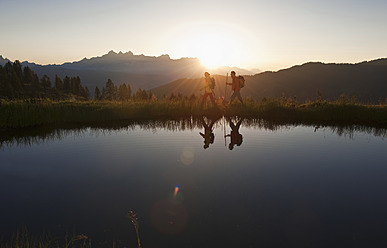 Austria, Salzburg, Couple walking near mountain lake at sunrise - HHF003774