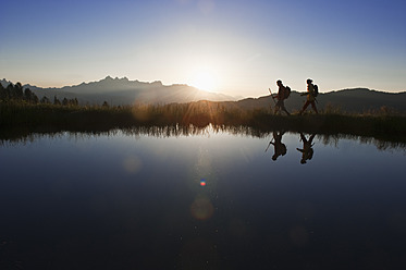 Austria, Salzburg, Couple walking near mountain lake at sunrise - HHF003776