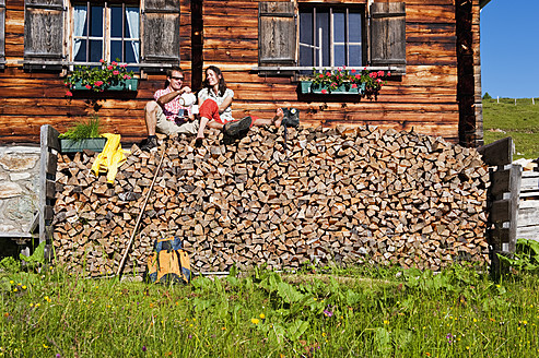 Österreich, Salzburg, Paar sitzt auf Baumstämmen bei Hütte - HHF003798