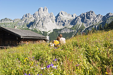 Österreich, Salzburg, Filzmoos, Pärchen sitzend und ruhend auf Almwiese - HHF003819