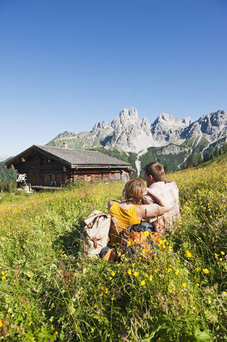 Österreich, Salzburg, Filzmoos, Pärchen sitzend und ruhend auf Almwiese, lizenzfreies Stockfoto