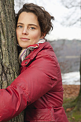 Germany, Berlin, Wandlitz, Mid adult woman hugging tree, portrait - WESTF018255