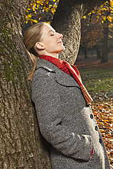 Deutschland, Berlin, Wandlitz, Mittlere erwachsene Frau lehnt mit geschlossenen Augen an einem Baum - WESTF018310