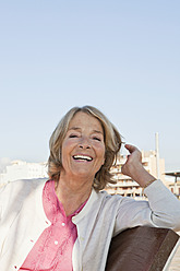 Spanien, Mallorca, Seniorin auf Bank am Meer sitzend, lächelnd, Porträt - SKF000779