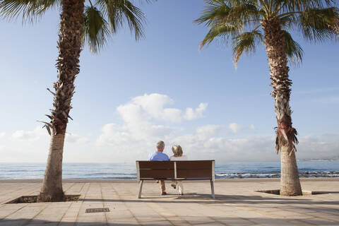 Spanien, Mallorca, Älteres Paar sitzt auf Bank am Meer, lizenzfreies Stockfoto