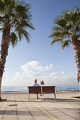 Spanien, Mallorca, Älteres Paar sitzt auf Bank am Meer - SKF000802