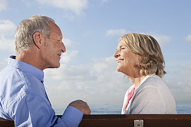 Spain, Mallorca, Senior couple sitting on bench at sea shore, smiling - SKF000807
