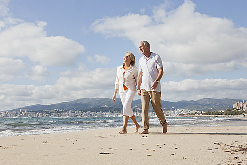 Spanien, Mallorca, Älteres Paar geht lächelnd am Strand entlang - SKF000832