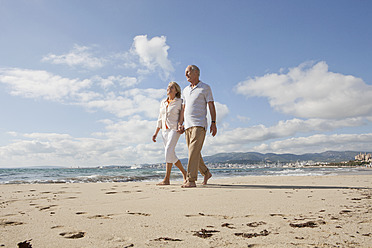 Spain, Mallorca, Senior couple walking along beach, smiling - SKF000833