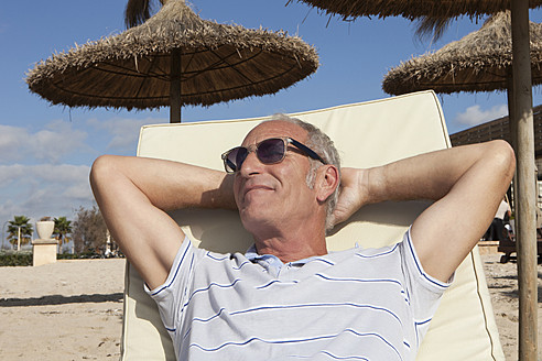 Spain, Mallorca, Senior man resting on deck chair at beach - SKF000850