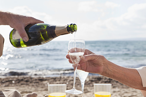 Spain, Mallorca, Senior couple drinking sparkling wine at beach - SKF000858