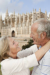 Spanien, Mallorca, Palma, Senior Paar lächelnd mit Kathedrale Santa Maria, Portrait - SKF000865