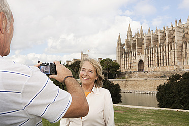 Spain, Mallorca, Palma, Senior couple smiling taking picture with Cathedral Santa Maria - SKF000869