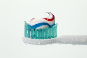 Elektrische Zahnbürste mit Zahnpasta vor weißem Hintergrund, Nahaufnahme - CSF015715