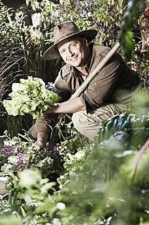 Österreich, Salzburg, Flachau, Älterer Mann hält Gemüse im Garten, lächelnd, Porträt - HHF003833