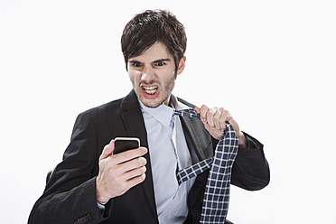 Businessman looking at mobile phone and removing tie - MAEF004245