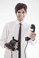 Junger Mann mit antikem Telefon, lächelnd, Porträt - MAEF004216