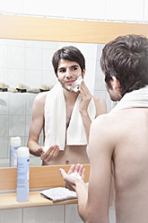 Junger Mann trägt im Badezimmer Rasierschaum auf - MAEF004224