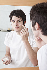 Young man applying cream on his face - MAEF004268