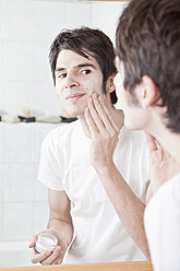 Young man applying cream on his face - MAEF004269