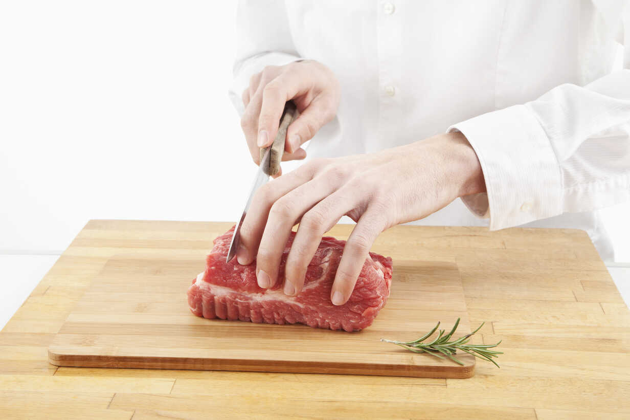 Chef cuts up meat on a cutting board with a sharp knife Stock Photo by  wirestock