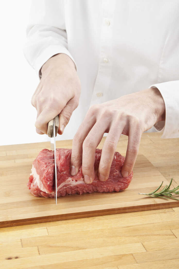 Man cutting meat on chopping board stock photo