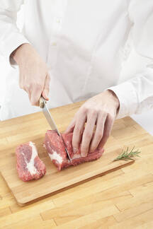 Man cutting meat on chopping board stock photo