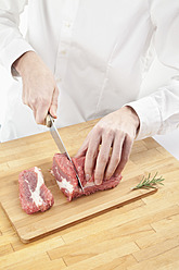 Man cutting meat on chopping board - MAEF004174