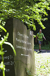 Europa, Deutschland, Nordrhein-Westfalen, Wanderwegschild mit Wanderer im Hintergrund - GWF001670