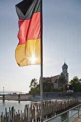 Deutschland, Wasserburg, Blick auf deutsche Flagge am Hafen und Kirche im Hintergrund - SH000645