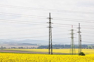 Germany, Bavaria, View of electricity pylon in rapeseed field - FOF003859