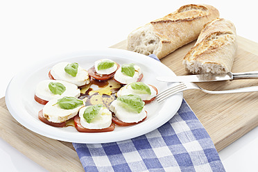 Mozzarella, bread, tomatoes slices with basil on chopping board - MAEF004300