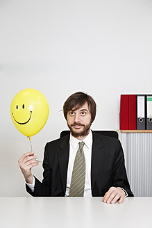 Deutschland, Geschäftsmann hält Smiley-Ballon - ANBF000071