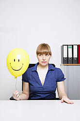 Deutschland, Geschäftsfrau hält Smiley-Ballon - ANBF000074