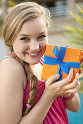 Spanien, Mallorca, Teenager-Mädchen hält Geschenkbox, lächelnd, Porträt - MFPF000042