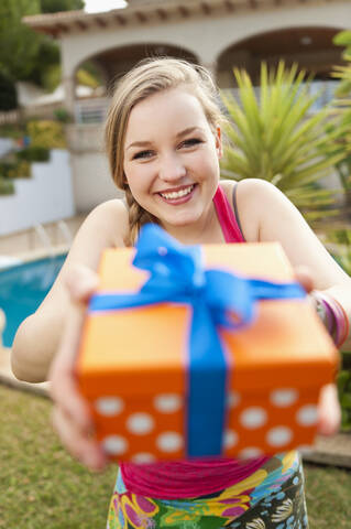 Spanien, Mallorca, Teenager-Mädchen hält Geschenkbox, lächelnd, Porträt, lizenzfreies Stockfoto