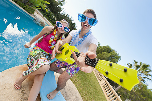 Spanien, Mallorca, Paar spielt am Swimmingpool, lächelnd - MFPF000055