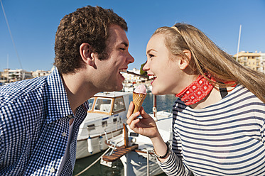 Spanien, Mallorca, Pärchen isst Eis am Hafen, lächelnd - MFPF000059